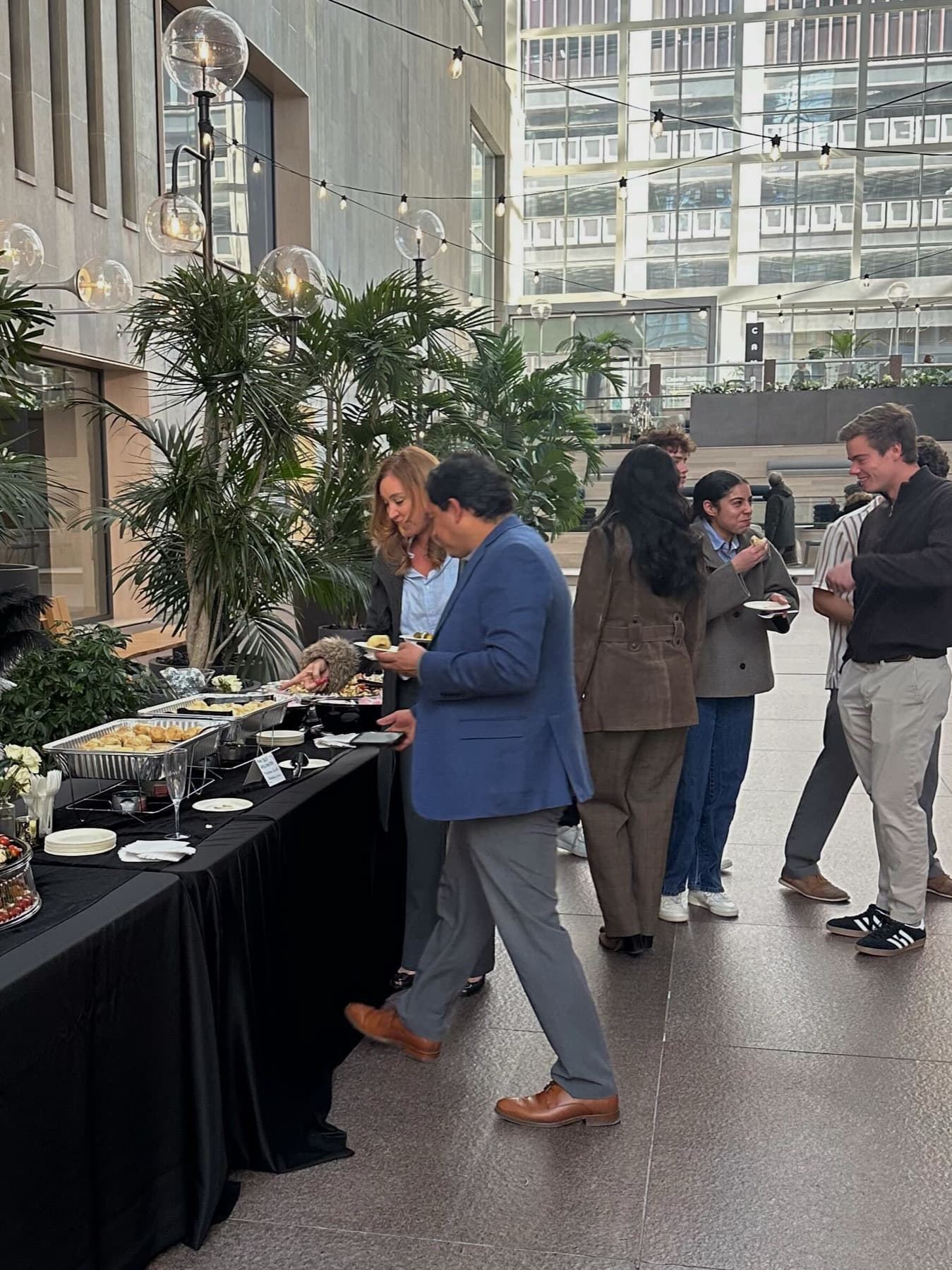 Catered reception in a Class A building atrium with string lights and palms