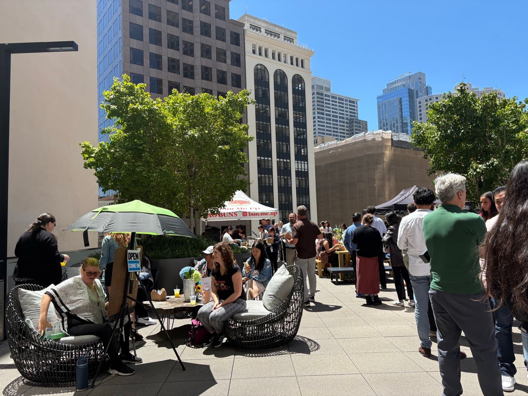 A busy tenant courtyard event at a Class A office tower on a sunny afternoon